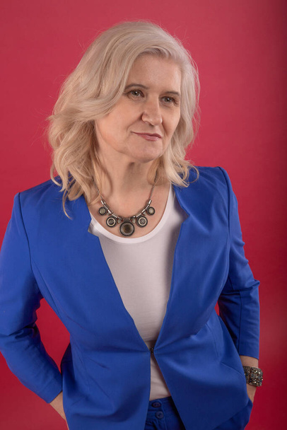 Adult beautiful woman in business suit. Red background. - Fotó, kép