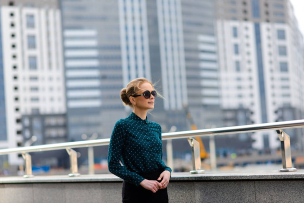 Beautiful young serious caucasian businesswoman in glasses while walking at break in the city - Foto, afbeelding