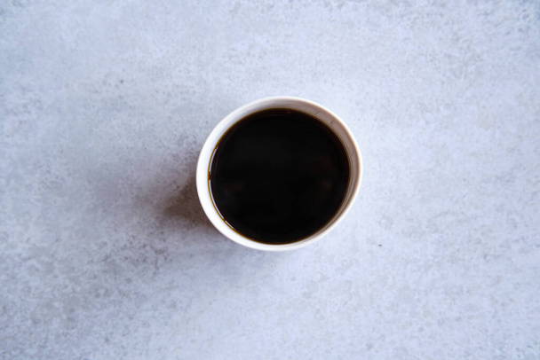 Tasse schwarzer Kaffee in einem handgemachten weißen Keramikbecher, weißer Marmorhintergrund - Foto, Bild
