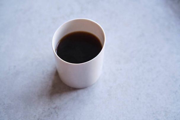 Tasse schwarzer Kaffee in einem handgemachten weißen Keramikbecher, weißer Marmorhintergrund - Foto, Bild