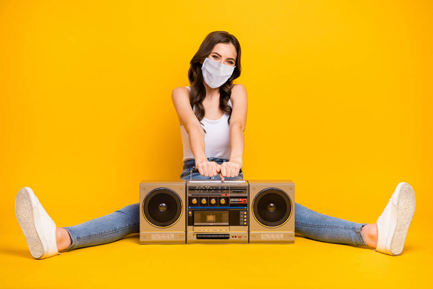 Full length photo of pretty lady sitting floor vintage recorder between spread legs wearing mask quarantine domestic time observation isolated bright vivid shine vibrant yellow color background - Фото, изображение