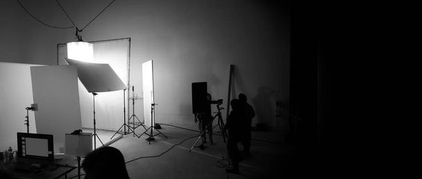 Shooting Studio für Fotograf und Creative Art Director mit Produktionsteam, das Beleuchtungsblitz und LED-Scheinwerfer auf Stativ und professionelles Equipment für Porträtmodell-Fotoshooting und Video-Online-Dreharbeiten einrichtet - Foto, Bild