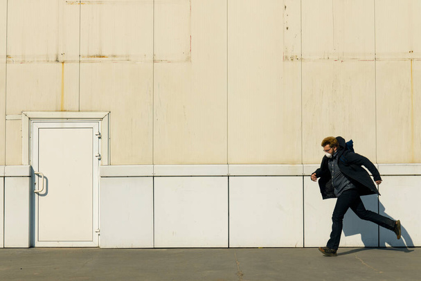 osamělý muž spustit z něčeho podél průmyslové špinavé továrny zeď pozadí kopírovat prostor - Fotografie, Obrázek