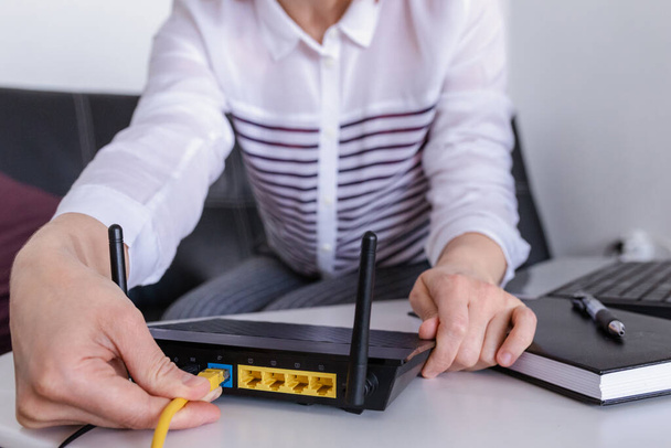 hand and lan network cable with people work on wireless router, - 写真・画像