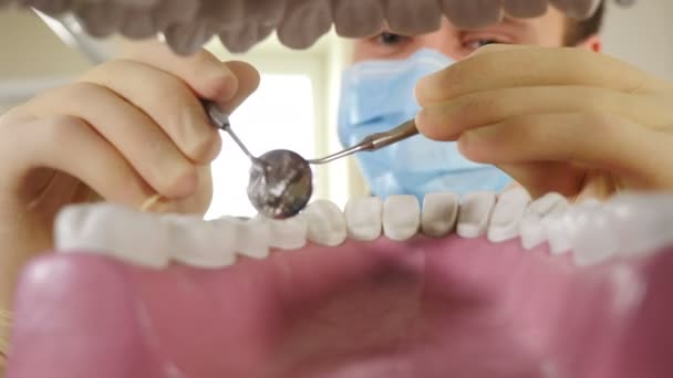 Személyes vagy beteg nézőpont, POV. Fogorvos keres a szájmodell és a gazdaság fogászati eszközök vizsgálatra. A fogászati klinikán. Közelkép a férfi fogorvosról. 4 k videó - Felvétel, videó