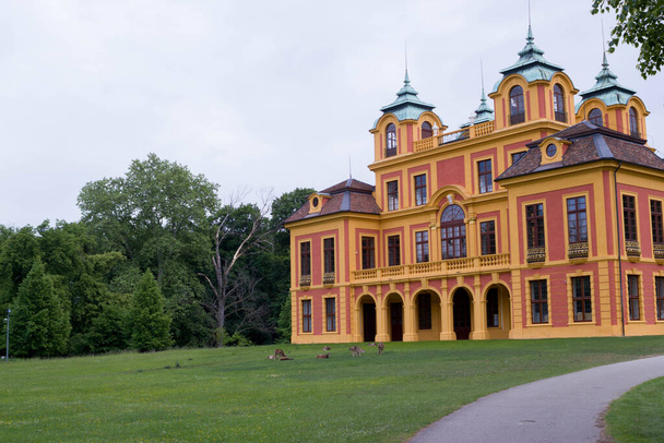18th century red and yellow fairytale castle "Schloss Favorite" in Ludwigsburg, Germany with deer on green lawn - Photo, Image