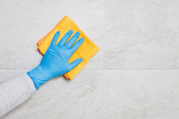 Young woman cleaning ceramic tiles with rag in bathroom. - Foto, Bild