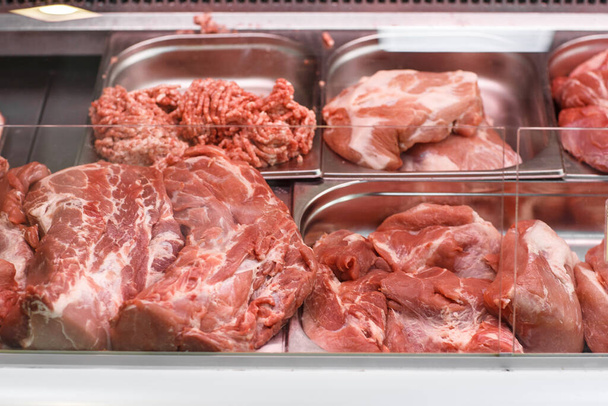 Heap of fresh meat food meat food background in supermarket store. Different types of raw meat in plastic boxes, leg of lamb on the bone, beef tail, beef neck, beef blade. Concept of farm and raw - Fotó, kép
