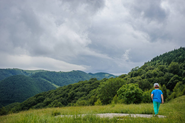 На задній стороні 6-річного блондинка біжить на вершині гори
 - Фото, зображення