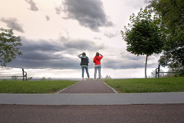 Zwei junge Mädchen stehen weg und schauen in den Himmel - Foto, Bild