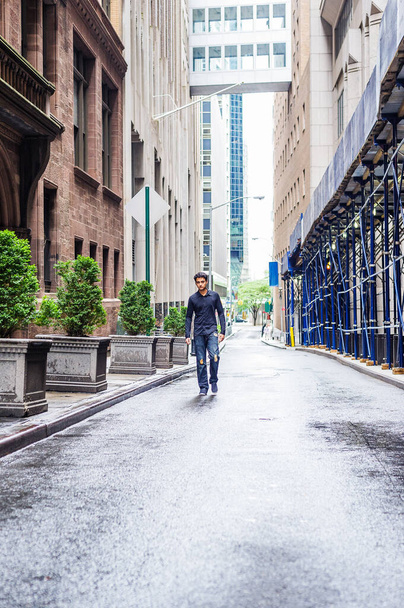 Día de lluvia - mojado, llovizna, sensación granulada. Adolescente americano indio oriental solitario con camisa negra de manga larga, vaqueros de moda rotos, zapato de tela, caminando por la calle estrecha de la ciudad de Nueva York
 - Foto, imagen