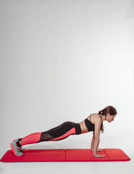 Athletic young woman doing exercise plank indoor, light background. - Foto, imagen