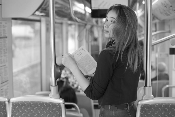Beautiful young woman in tram reading her book - Фото, изображение