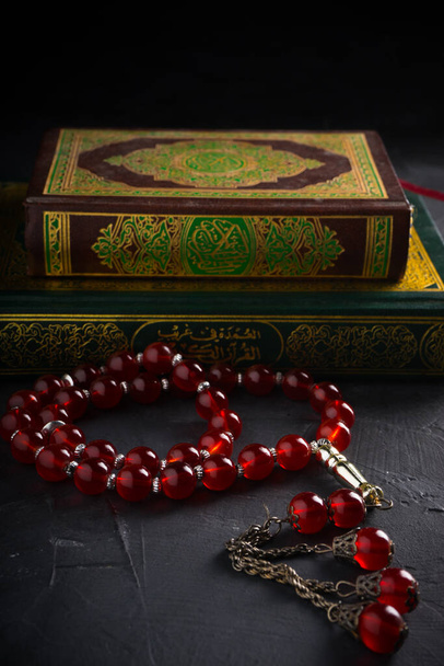Wiara w ideę islamu. Islamska święta księga Koran lub Kuran z różańcem lub tasbih na ciemnym tle. - Zdjęcie, obraz