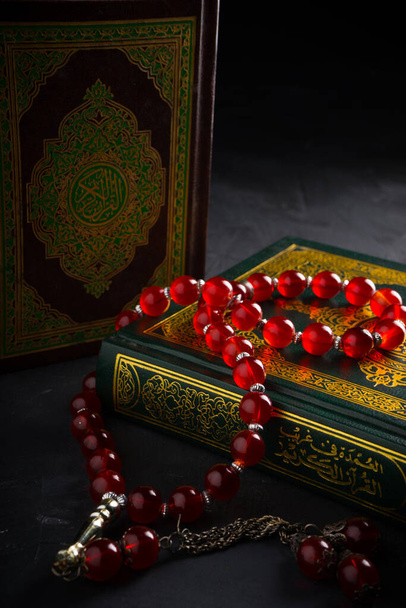 Geloof in de islam concept. Het islamitische heilige boek Koran of Kuran met rozenkransen of tasbih op donkere achtergrond. - Foto, afbeelding