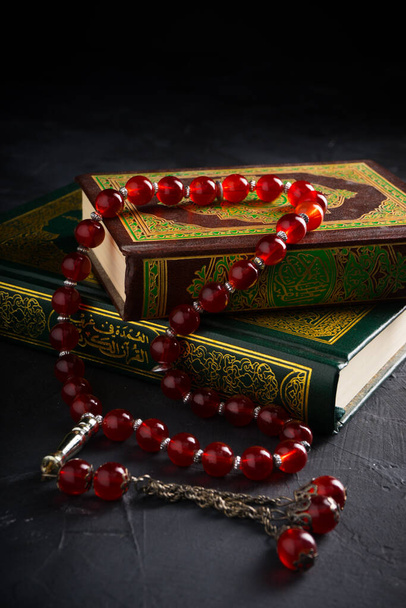 Wiara w ideę islamu. Islamska święta księga Koran lub Kuran z różańcem lub tasbih na ciemnym tle. - Zdjęcie, obraz