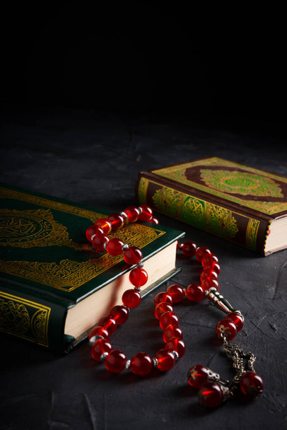 Glaube an den Islam. Das islamische heilige Buch Koran oder Kuran mit Rosenkranzperlen oder Tasbih auf dunklem Hintergrund. - Foto, Bild