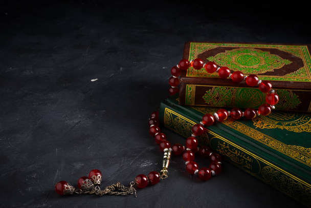 Віра в концепцію ісламу. Ісламська священна книга Коран або Куран з рожевими намистинами або тасбі на темному тлі. - Фото, зображення