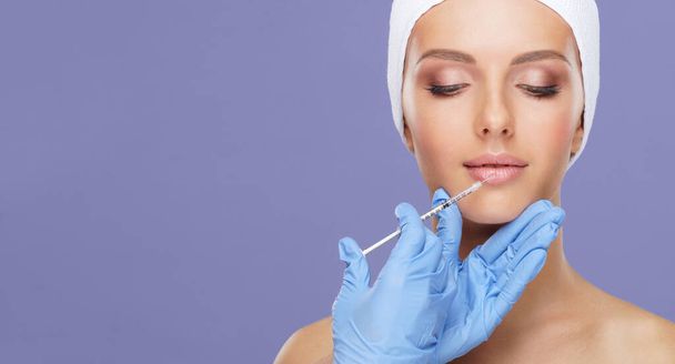 Doctor injecting in a beautiful face of a young woman. Plastic surgery, skin lifting and aesthetic medicine concept. - 写真・画像