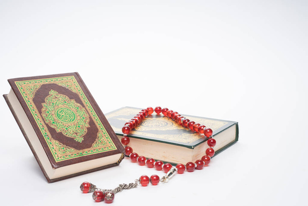Geloof in de islam concept. Het islamitische heilige boek Koran of Kuran met rozenkransen of tasbih geïsoleerd op witte achtergrond. - Foto, afbeelding