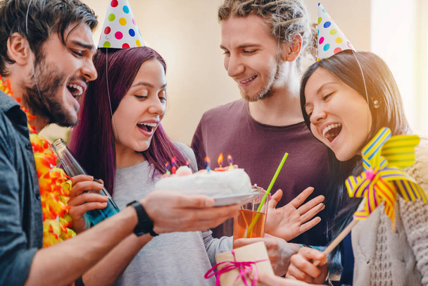 Close up photo of happy young girl celebrating birthday among friends while standing in room at home - Photo, image