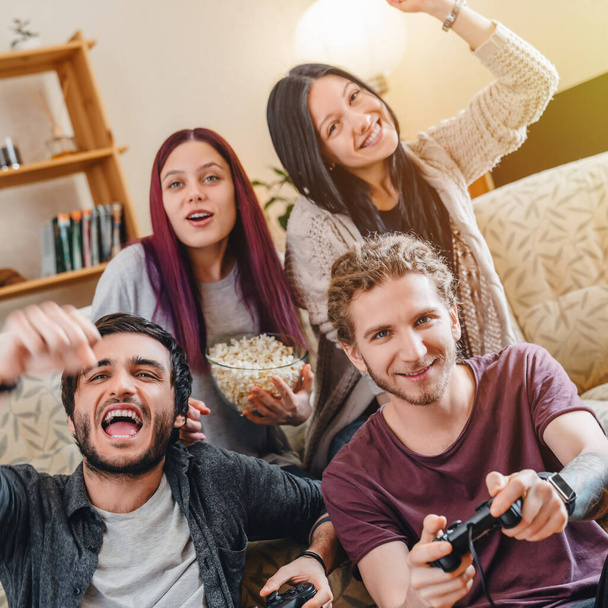 Group of young friends playing video games and celebrating together at home - Foto, imagen