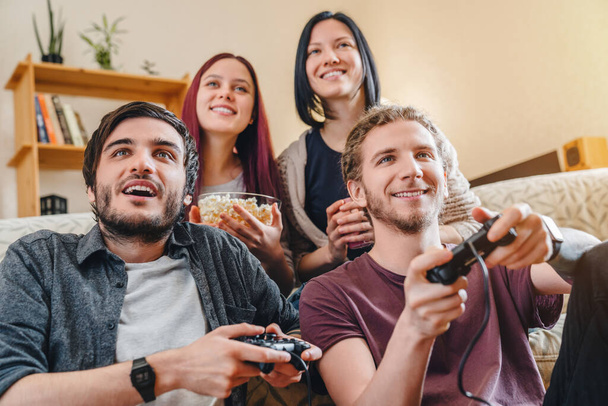 Multiethnic joyful group of young people playing games on console while having party at home - Fotografie, Obrázek