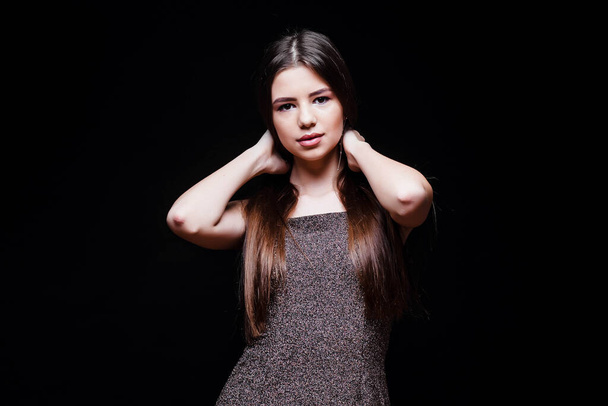 Young woman in a dress touches her hair isolated on black. Okay. Hair. The girl in the dress. Fashion. Natural cosmetics and beautiful bright makeup. Beautiful young girl. Portrait of a girl. - Photo, Image