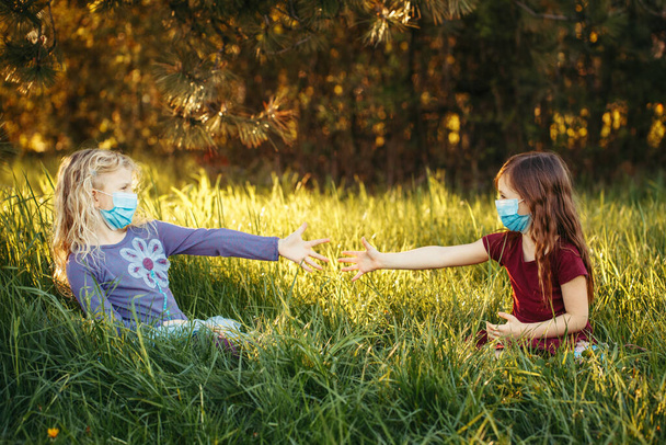 Cute girls friends in sanitary masks on faces. Preschool children kids wearing protective mask against coronavirus. Social  physical distance and health protection during covid-19 quarantine. - Foto, Bild