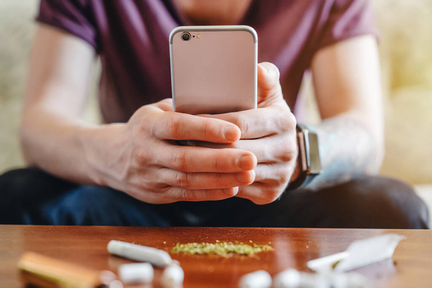 Young man making photo on his mobile phone of his joint and weed - Φωτογραφία, εικόνα