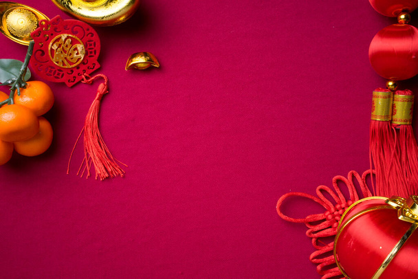 Chinese New Year decorations with red background with assorted festival decorations. Chinese characters means abundant of wealth, prosperity and luck. Flat lay. - Photo, Image