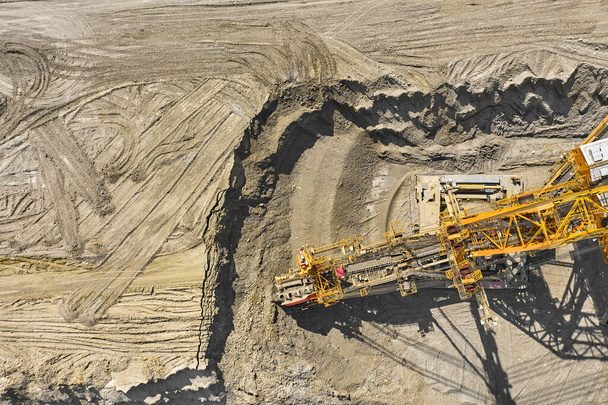 Doğal kaynak madenciliği yapan büyük bir ağır ekipman makinesinin havadan görüntüsü. Kova tekerleği kazıcısıyla kömür madenciliği. Ağır sanayi  - Fotoğraf, Görsel
