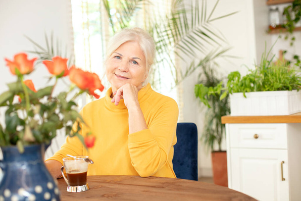 Happy smiling senior woman with hot coffee relaxing at home. - Foto, Bild