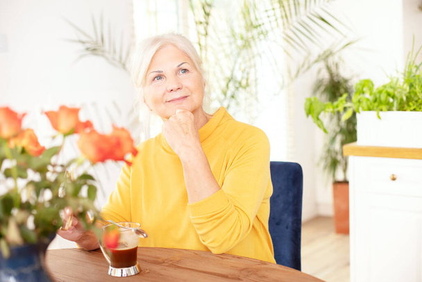 Happy smiling senior woman with hot coffee relaxing at home. - Foto, imagen