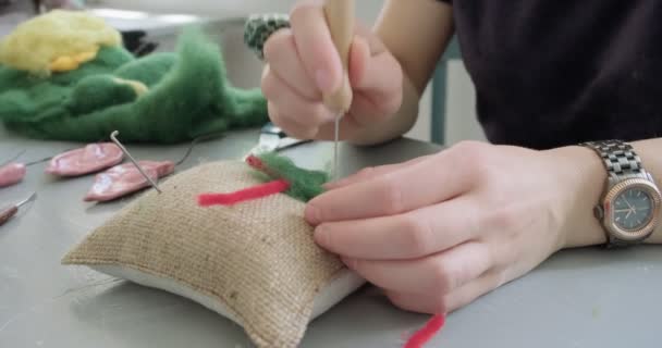Egy nő gyapjú játékszert készít az asztalnál, közelről. Nő ül, és létre tölgyfa baba otthon. Tű Felted Kézzel készített és kreatív készségek - Felvétel, videó