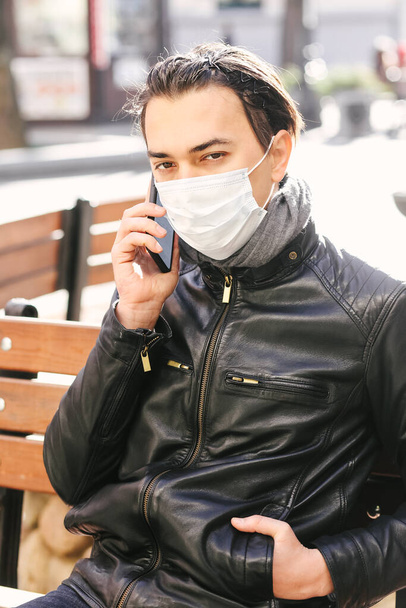 Close up Man with protective face mask using mobile phone in the city street. Responsible behavior during World Covid-19 Pandemic. Virus protection concept - Foto, Bild