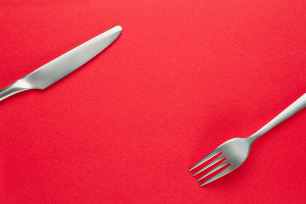 Tenedor y cuchillo en rojo. Plantilla de tema de alimentos y fondo
 - Foto, imagen