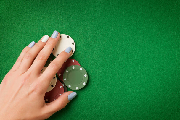 Woman hand holding poker chips on green casino felt background. Gambling theme image with copy space - Fotografie, Obrázek