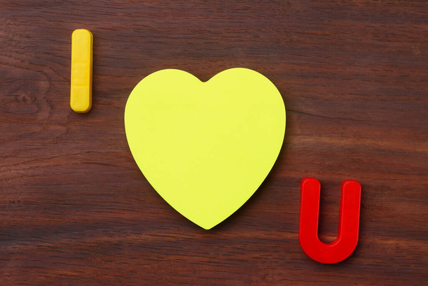 Cartas I y U con una etiqueta en blanco en forma de corazón simbólico. Mensaje corto Te amo. Contexto
 - Foto, imagen