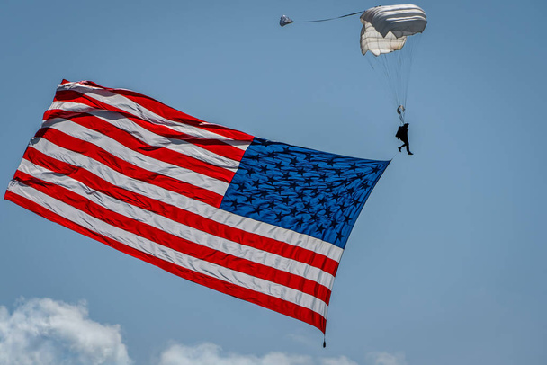 カリフォルニア州サンディエゴでアメリカ国旗を掲揚するパラシュートのシルエット. - 写真・画像