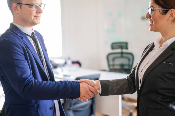 Handshake business man and woman at the conclusion of a successful transaction. Office staff in suits during a greeting. Successful job interview. - 写真・画像