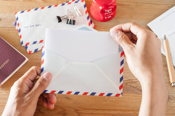 Рука крупным планом открывает конверт на рабочем столе
 - Фото, изображение