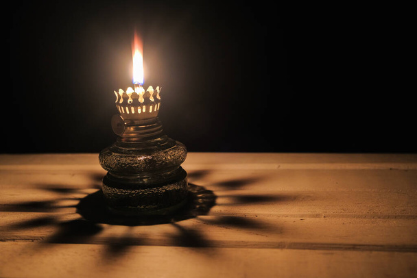 美しい影とテーブルの上に暗闇の中で古いオイルランプの照明を燃焼 - 写真・画像