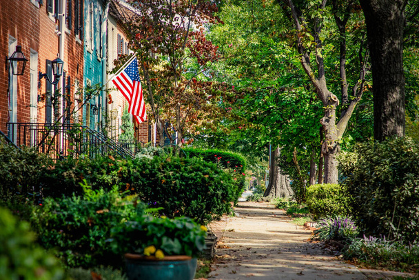 Uma bandeira voando sobre uma rua da Virgínia com calçadas de paralelepípedos e casas históricas de tijolos vermelhos
. - Foto, Imagem