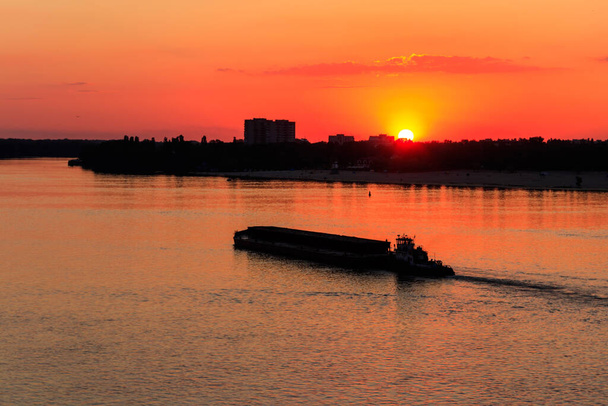 Remolcador empujando una larga barcaza pesada en el río Dnieper al atardecer - Foto, Imagen