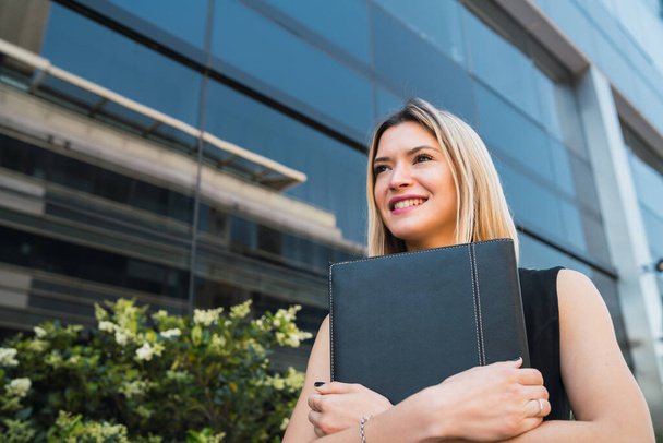 Portrait of young business woman holding clipboard while standing outdoors at the street. Business concept. - Foto, Bild