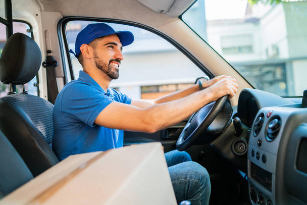 Portrait of a delivery man driver driving van with cardboard boxes on seat. Delivery service and shipping concept. - Φωτογραφία, εικόνα