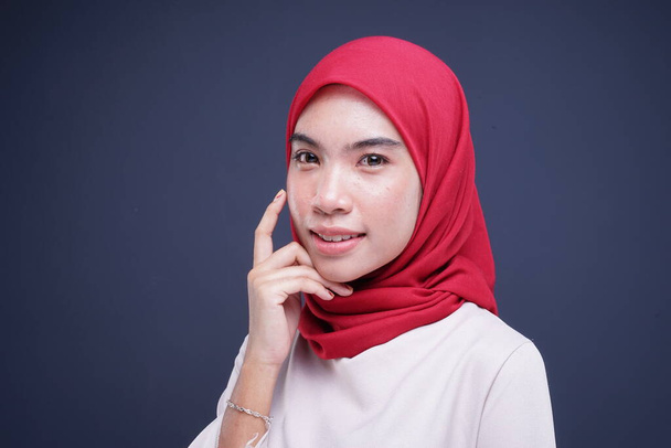 Imagen de una hermosa modelo femenina musulmana en un kebaya moderno crema con hiyab rojo, un vestido tradicional musulmán asiático aislado sobre fondo gris. Eidul fitri moda y estilo de vida concepto de retrato
. - Foto, imagen