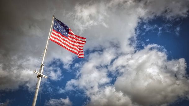 風の強い日にポールを飛ぶ15つ星のアメリカ国旗. - 写真・画像