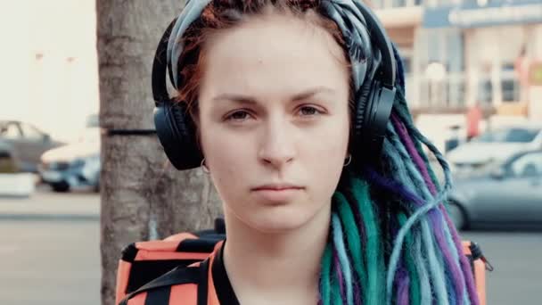 girl courier in headphones and dreadlocks - Кадры, видео